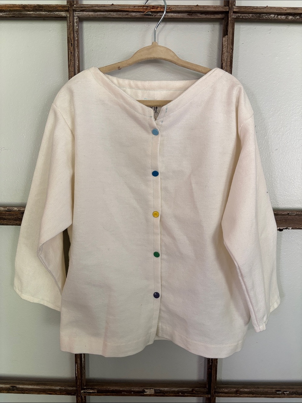 Cream colored child’s linen cardigan with multicolor buttons